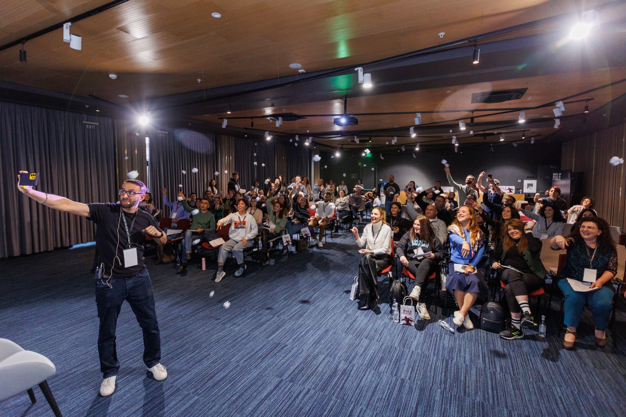 Paddy taking a selfie with a conference audience throwing paper aeroplanes
